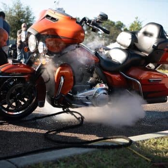 Orange touring motorcycle being steam detailed