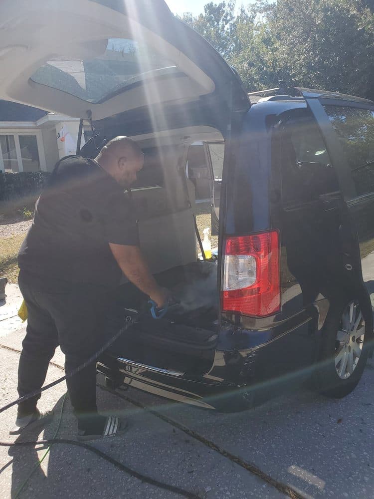 Revival Steam Detailing working on the rear cargo area of a black SUV